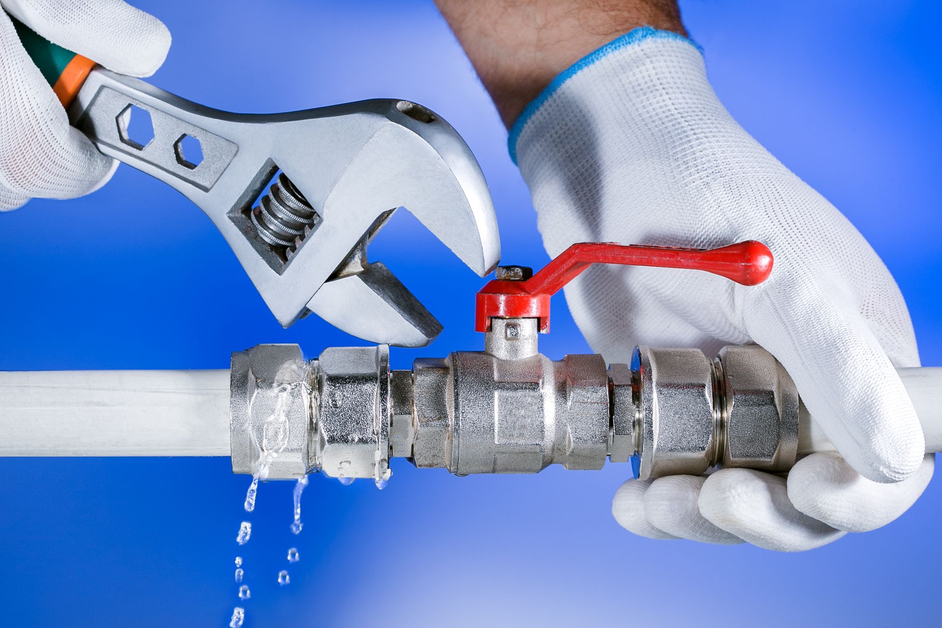 A plumber is fixing a leaking pipe with a wrench