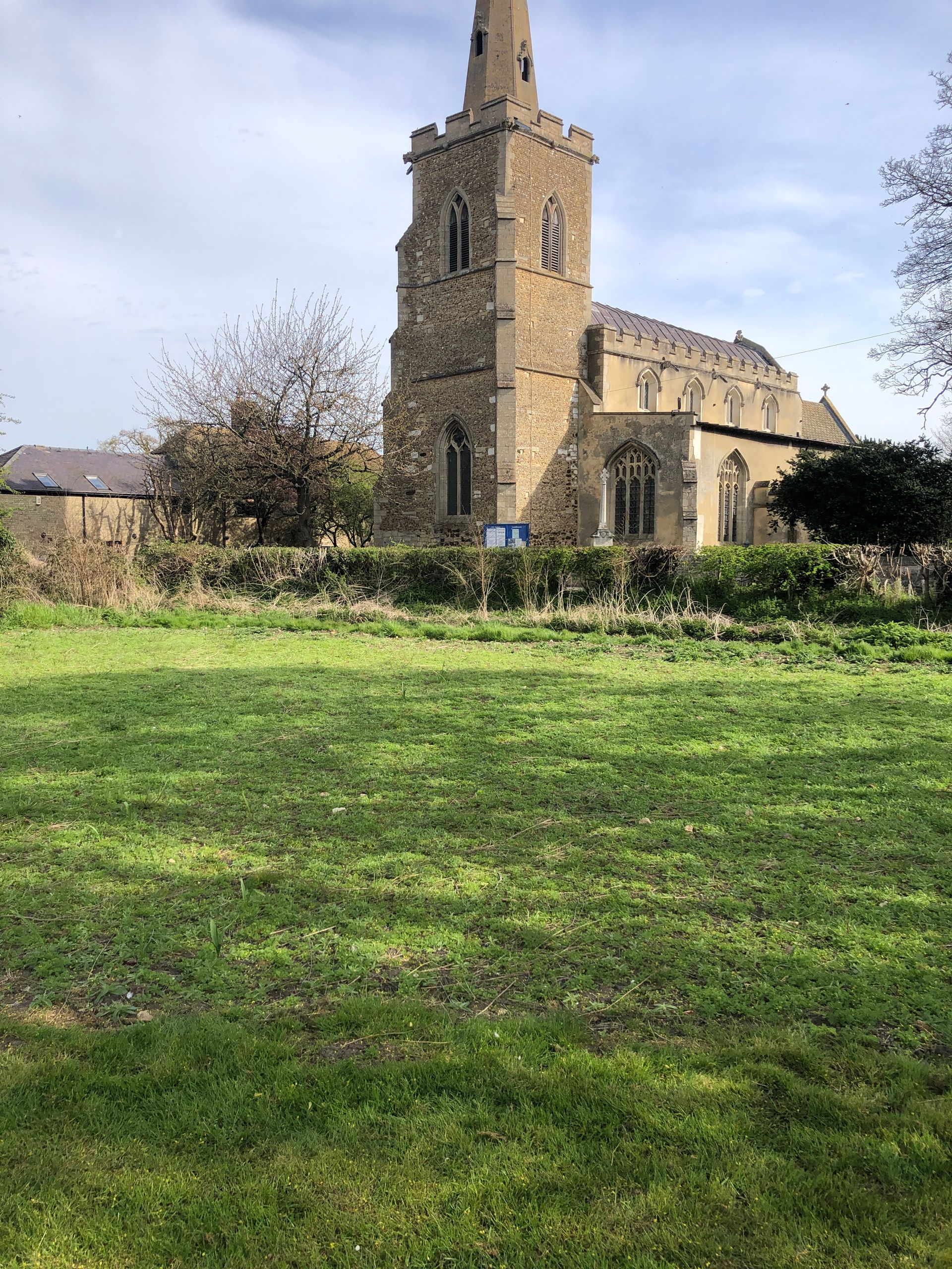 A large stone church is surrounded by a lush green field.