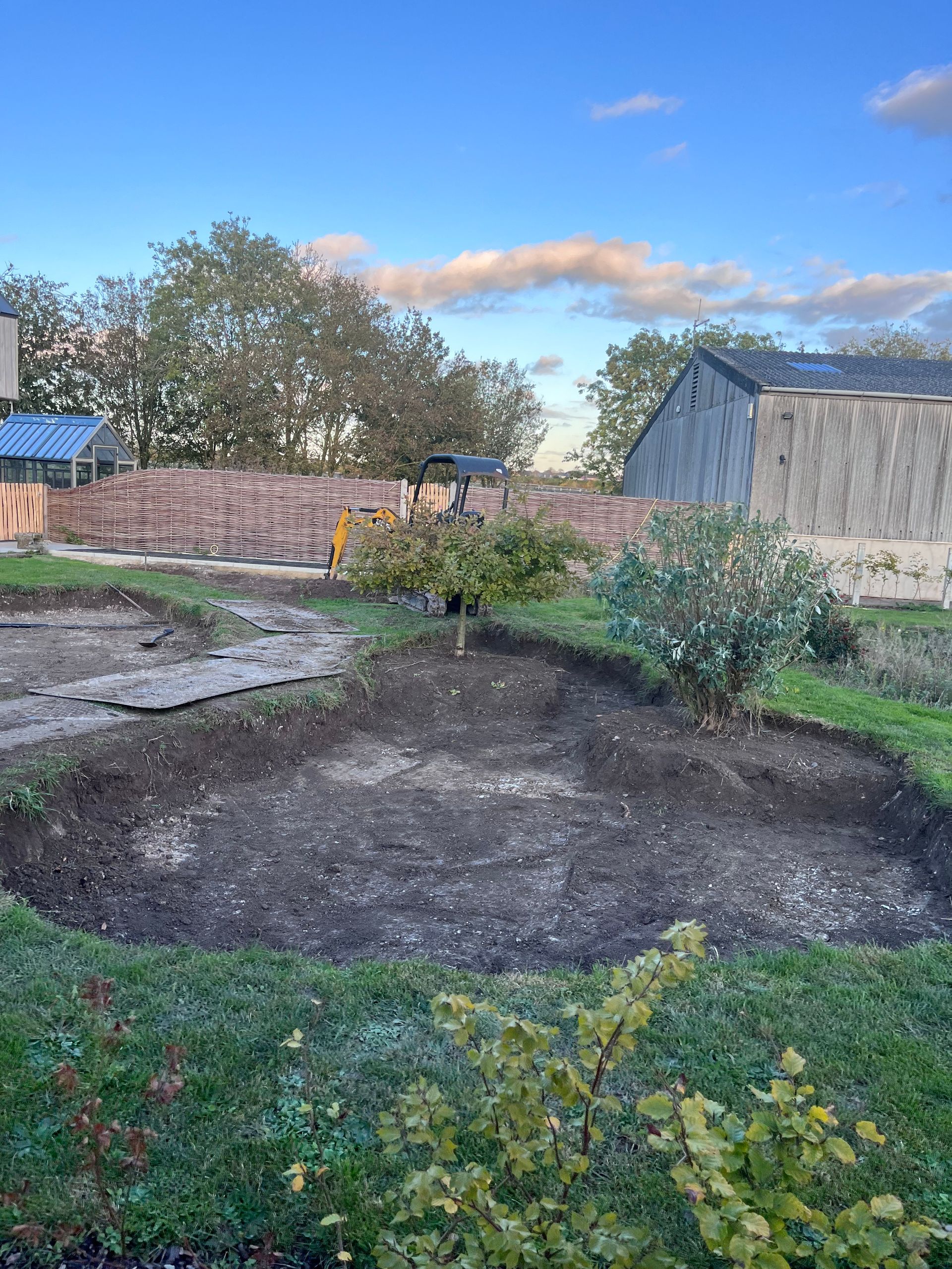 There is a large hole in the ground in the middle of a garden.
