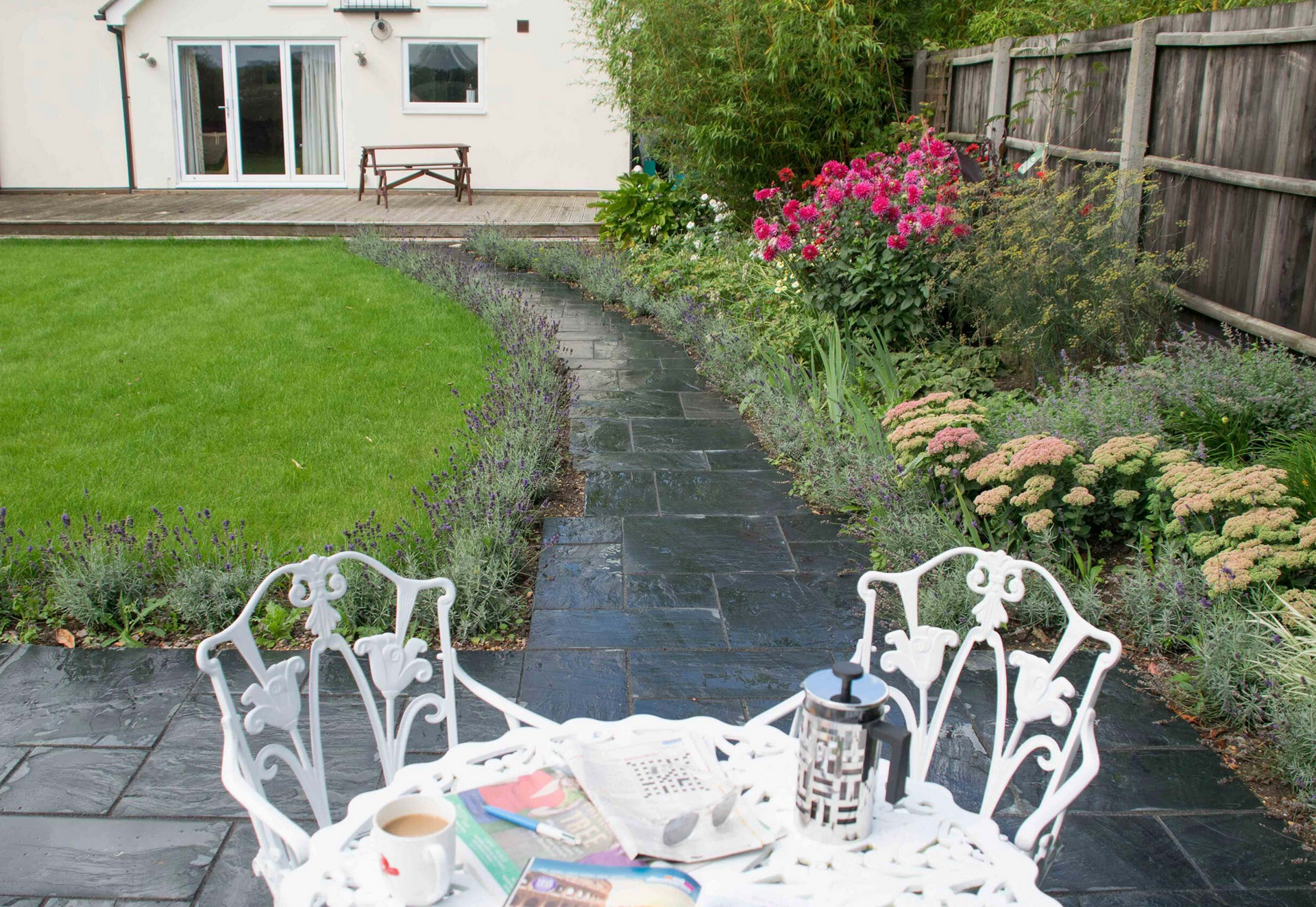 A table and chairs in a garden with a house in the background