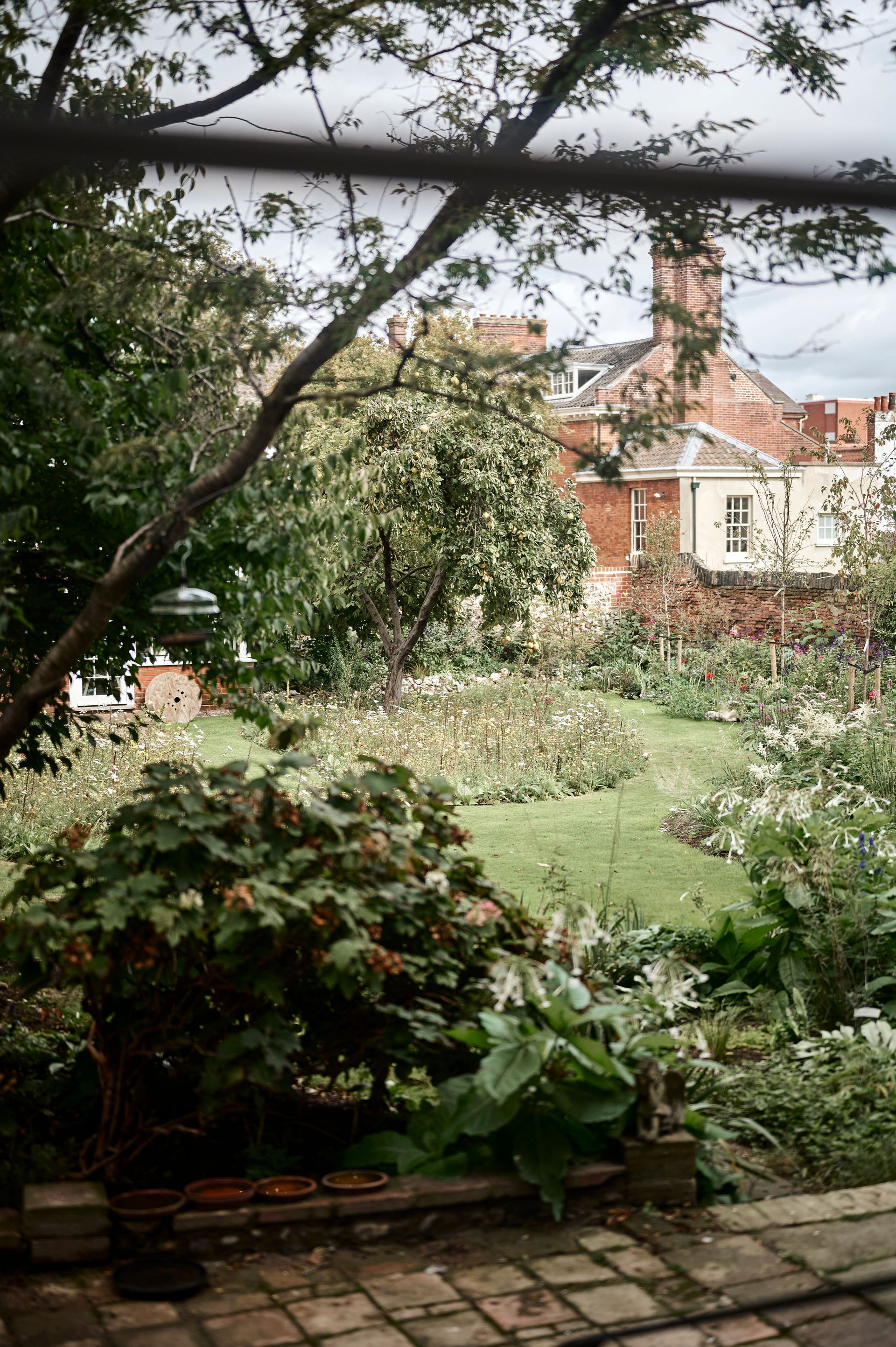 A large house is sitting in the middle of a grassy field next to a dirt road.