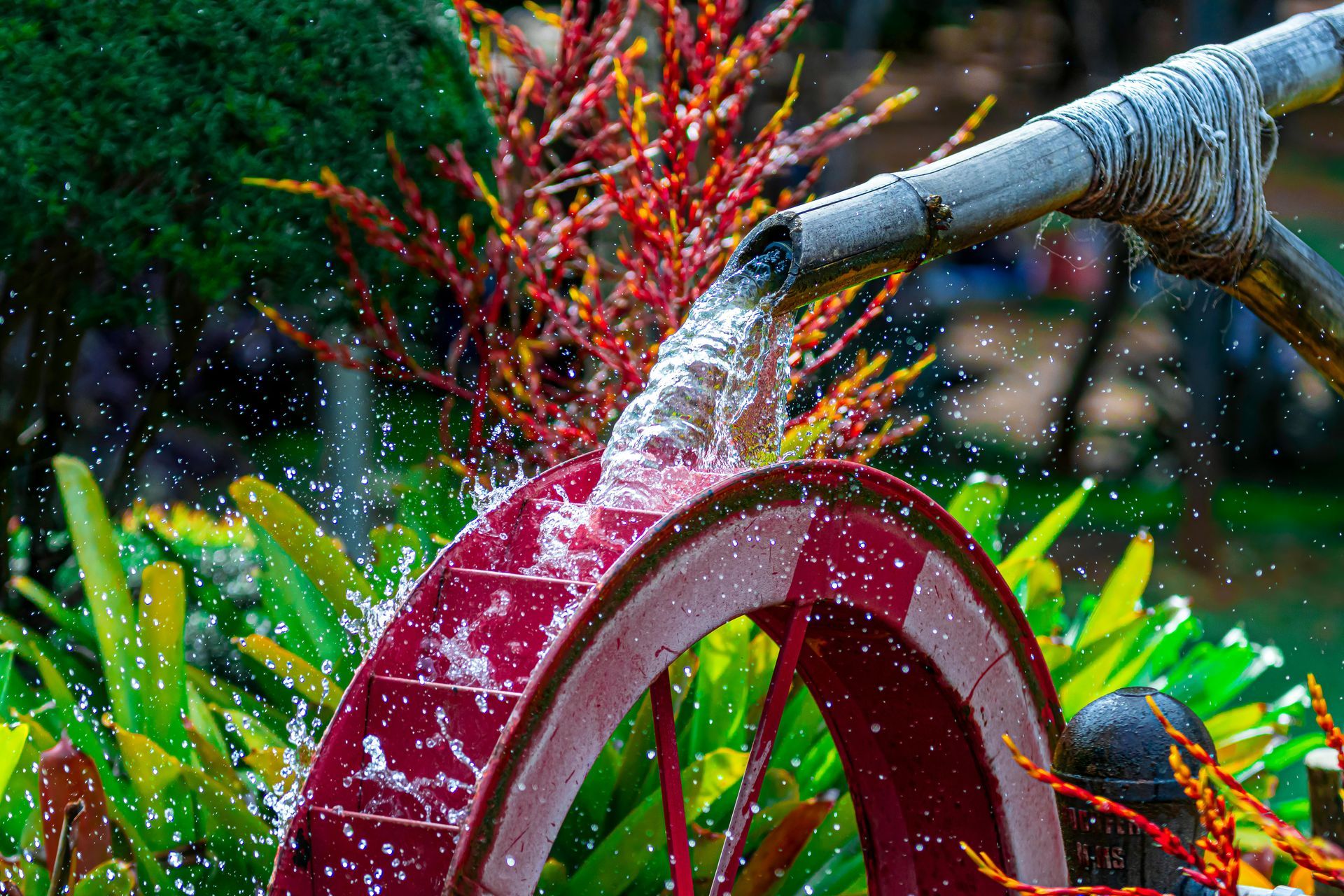 A water wheel is being sprayed with water in a garden.