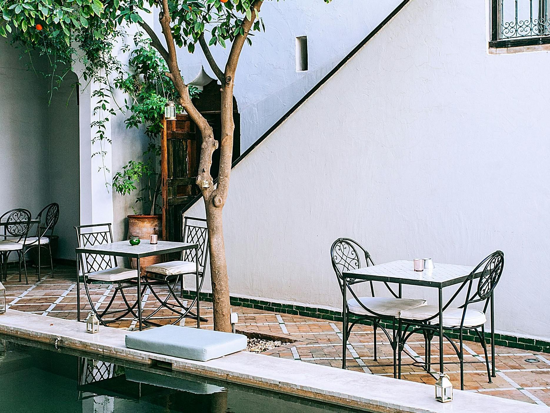 A patio with tables and chairs next to a pool