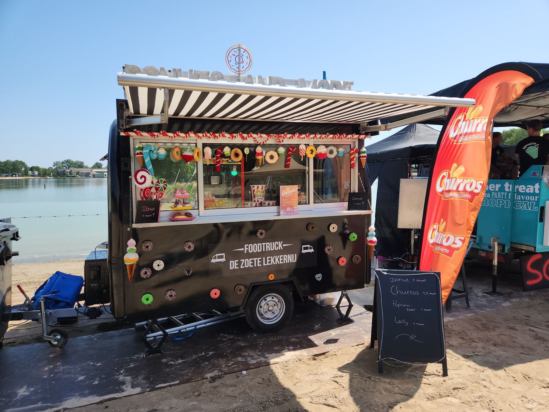 Een foodtruck staat geparkeerd op het strand naast een meer.
