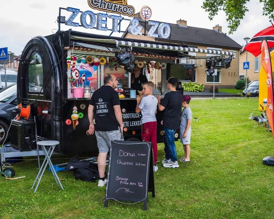 Een groep mensen staat voor een foodtruck.