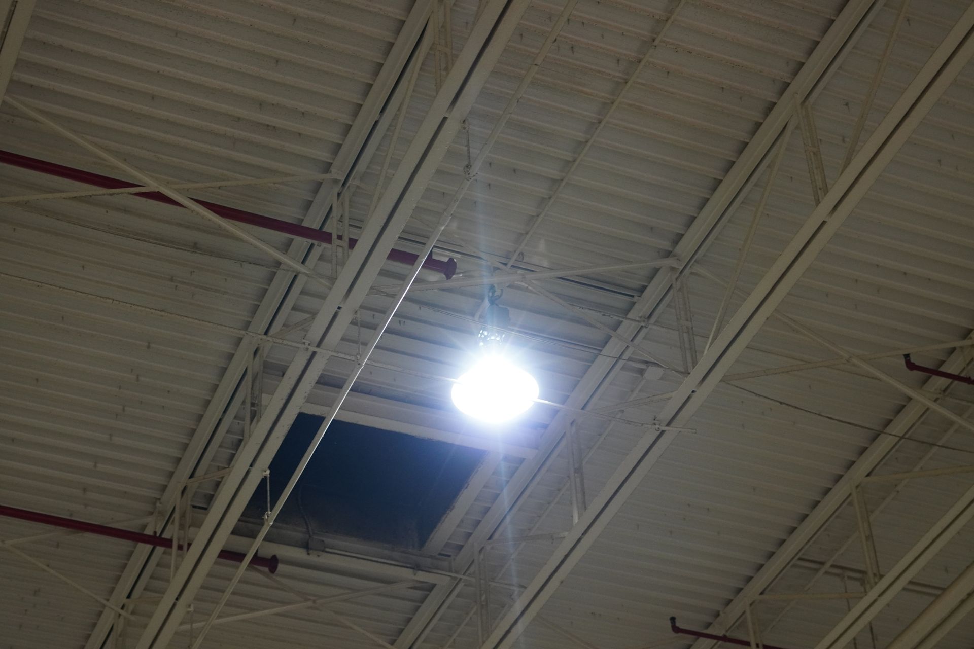 Warehouse interior with long, reflective floor, overhead lighting, and machinery.