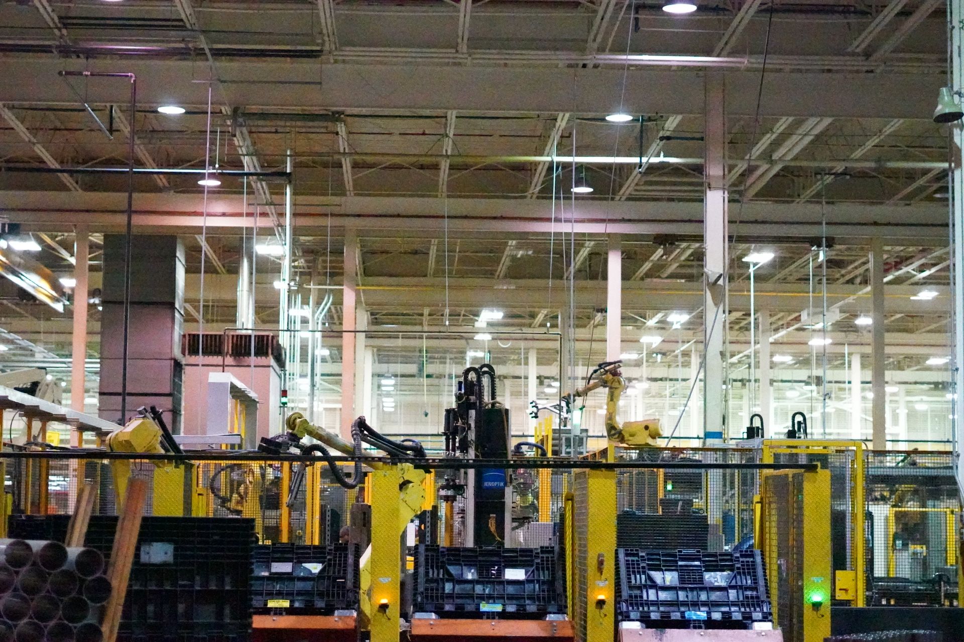 Power lines and towers silhouetted against a bright, sunny sky above lush green trees.