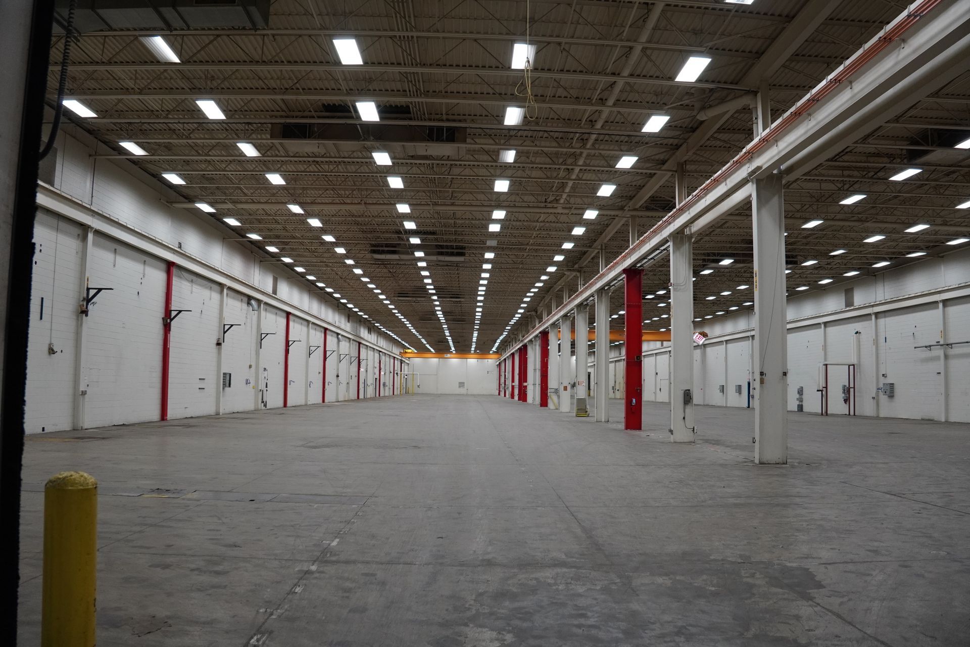 Two workers inspect machinery in a factory. One holds a circuit board, the other a screwdriver, both wearing safety helmets.