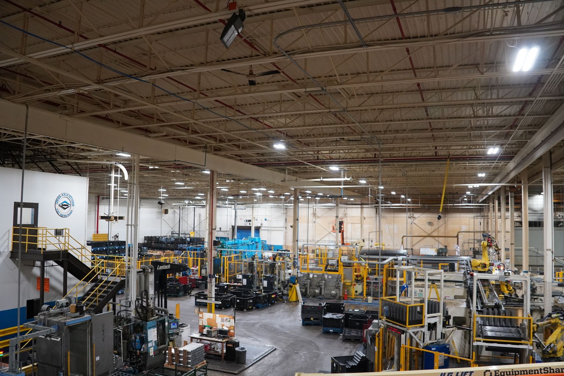 Person replacing lightbulb in a black lampshade, surrounded by green plants.