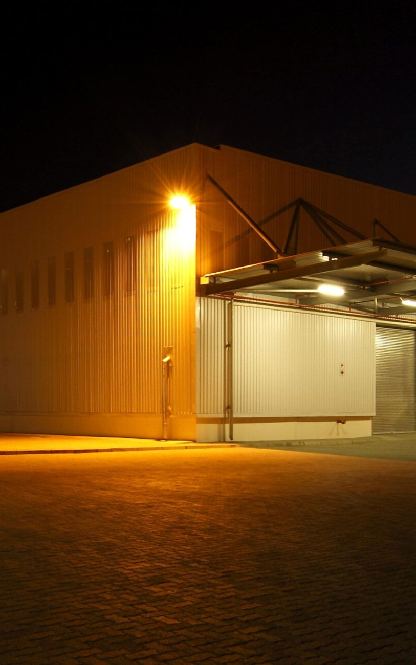 Warehouse exterior at night, lit by orange streetlights.