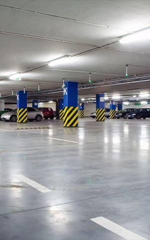 Indoor parking garage with cars parked, concrete floor, support pillars.