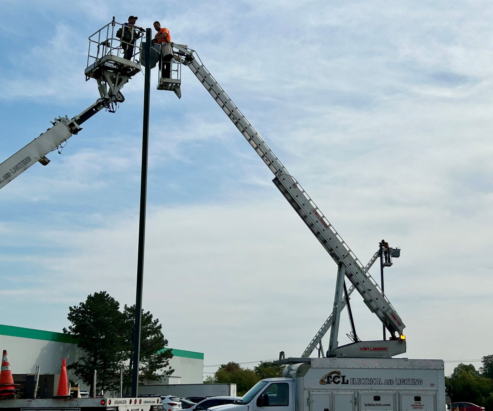 Electrician in blue hard hat, safety glasses, and gloves working on an electrical panel.