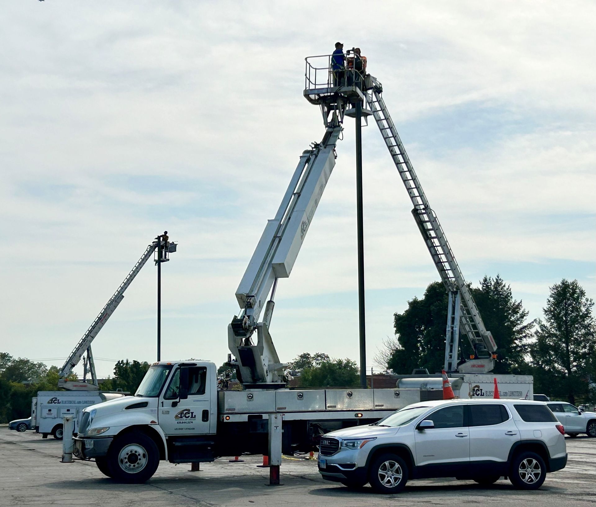 Lineman in bucket truck working on power lines near houses and green lawn.