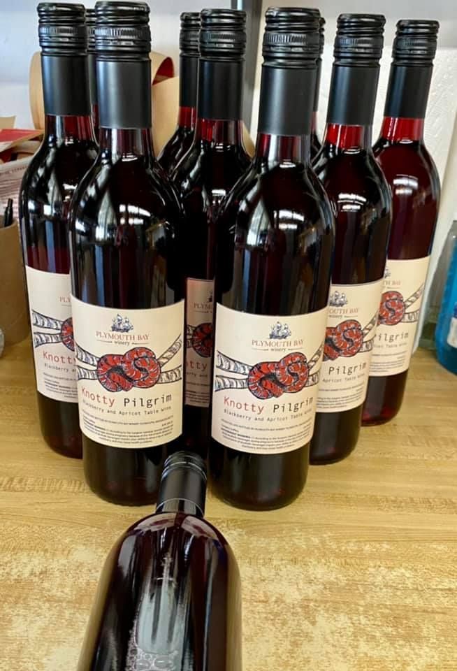 Bottles of red wine with black caps and white labels reading 