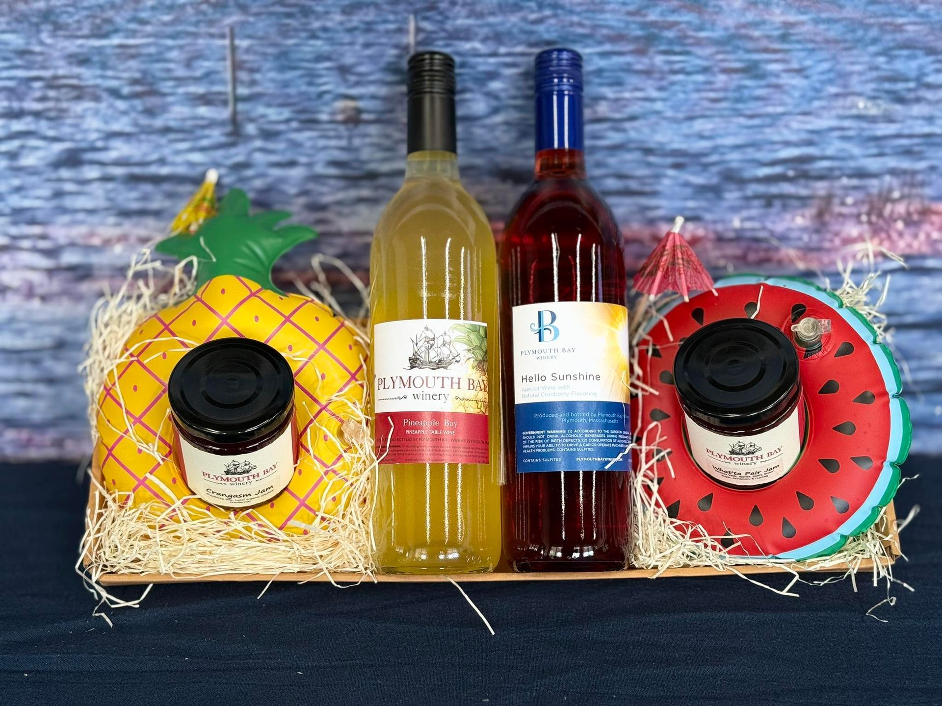 Wine gift basket: Two wine bottles, pineapple and watermelon decorations, two jars of jam.