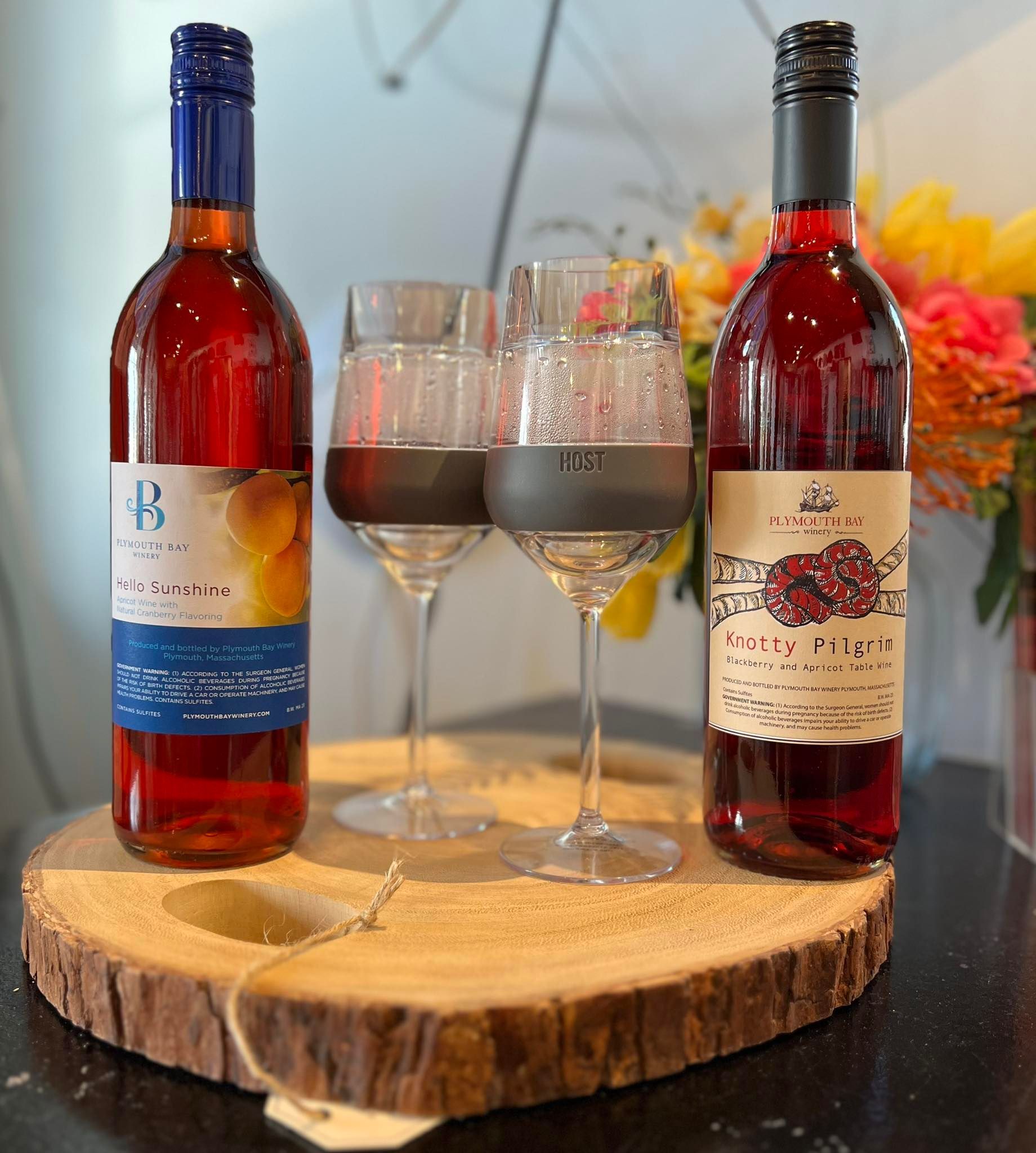Two bottles of red wine with two glasses on a wooden stand.