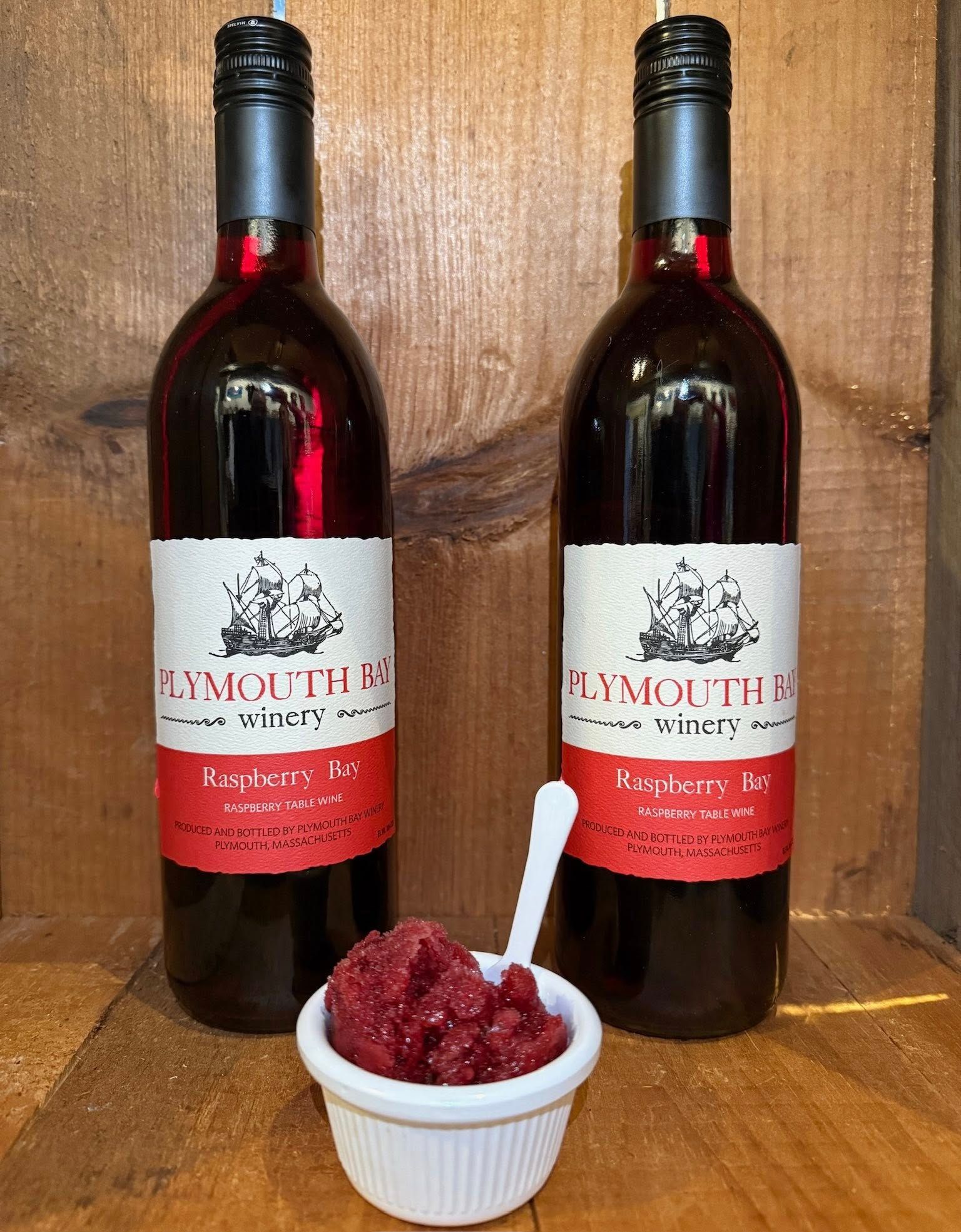 Two wine bottles and a small bowl of raspberry jam. Labels read 