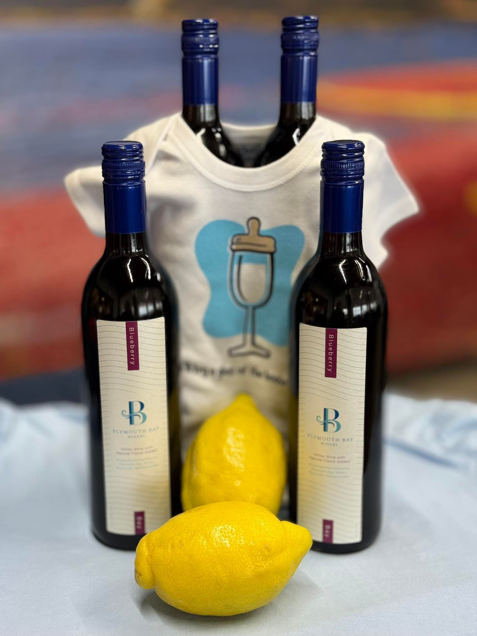 Four wine bottles with a baby onesie and lemons.