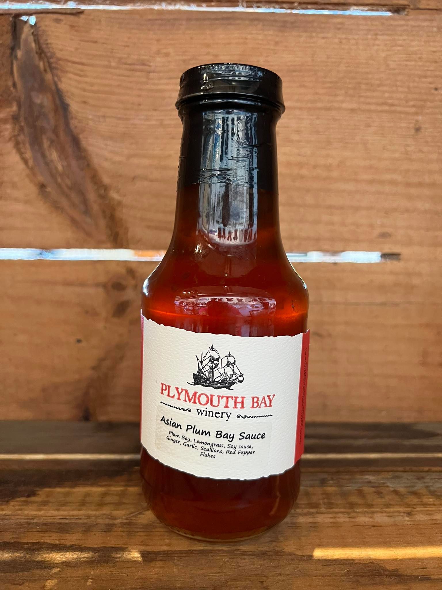 Bottle of Plymouth Bay hot sauce against a wooden background.