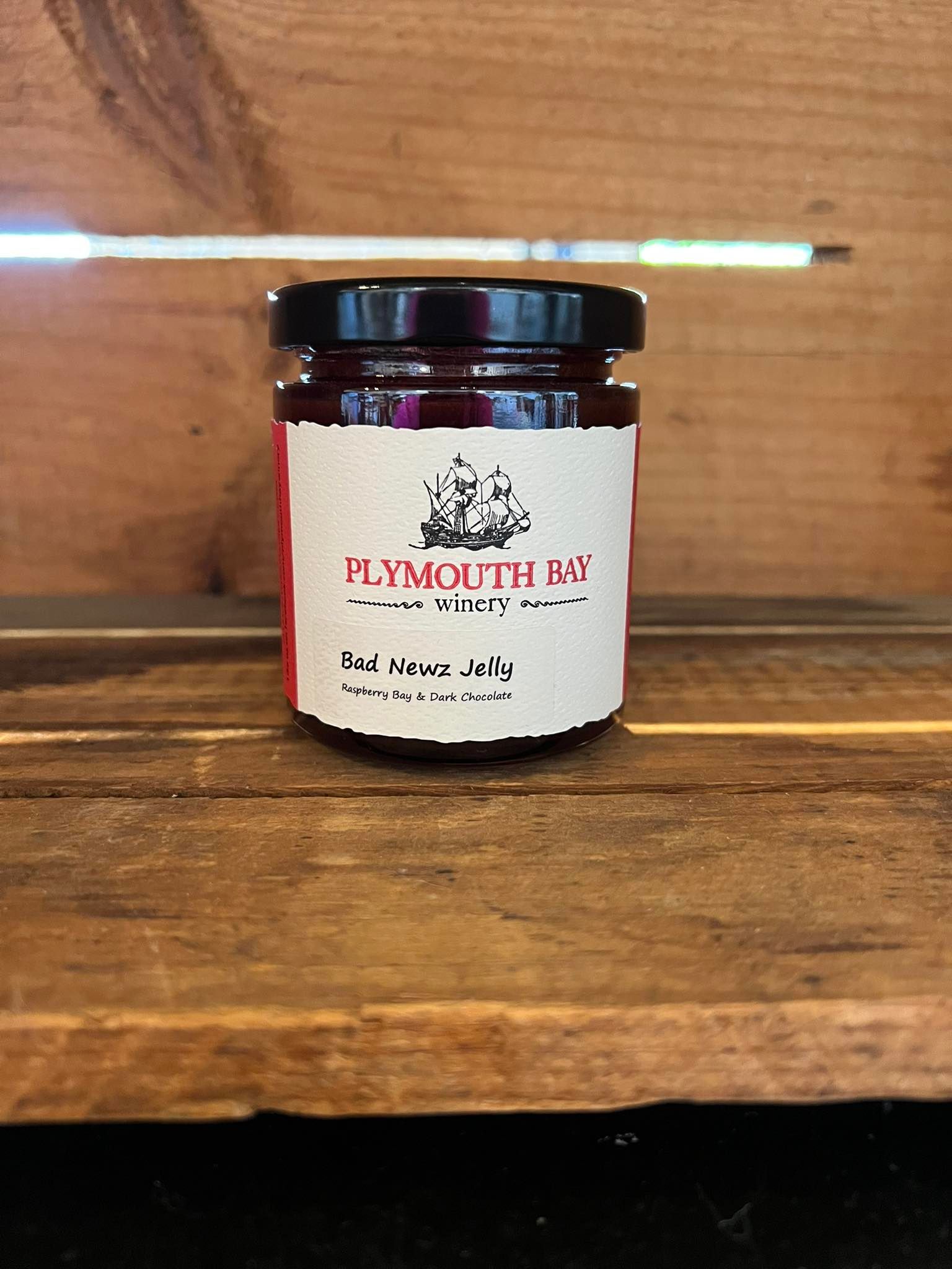Jar of jam with red label on a wooden surface.