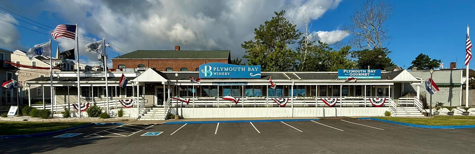 A diner with a parking lot and flags under a partly cloudy sky.