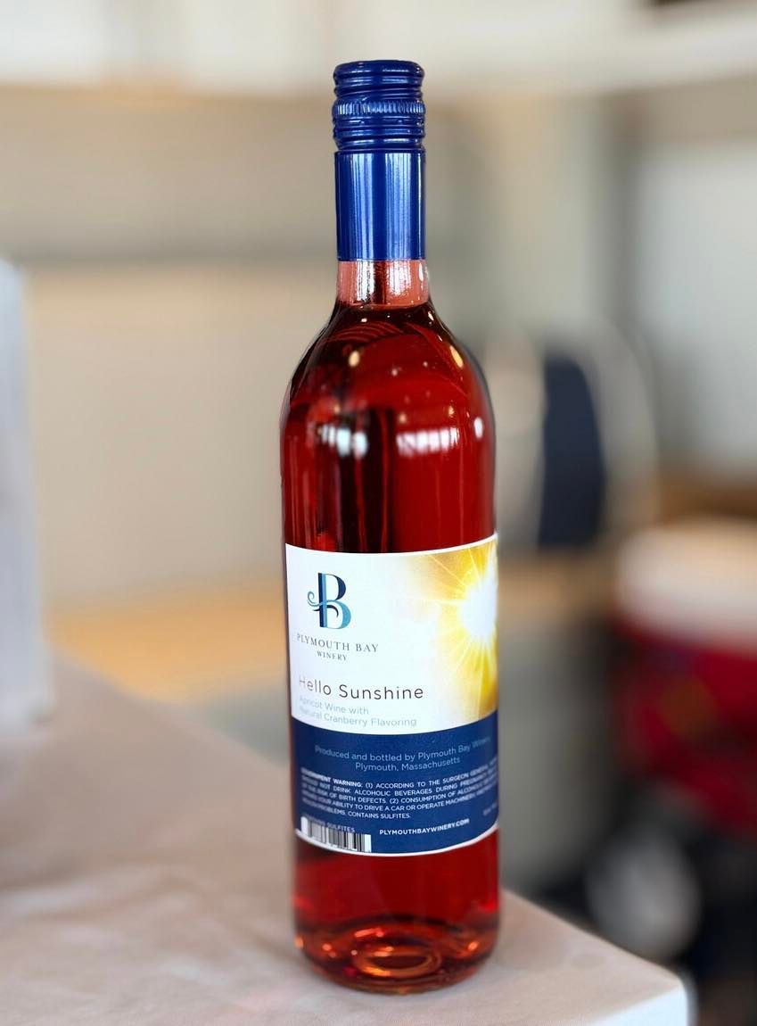 Bottle of pink wine with blue cap and label, sitting on a white surface.