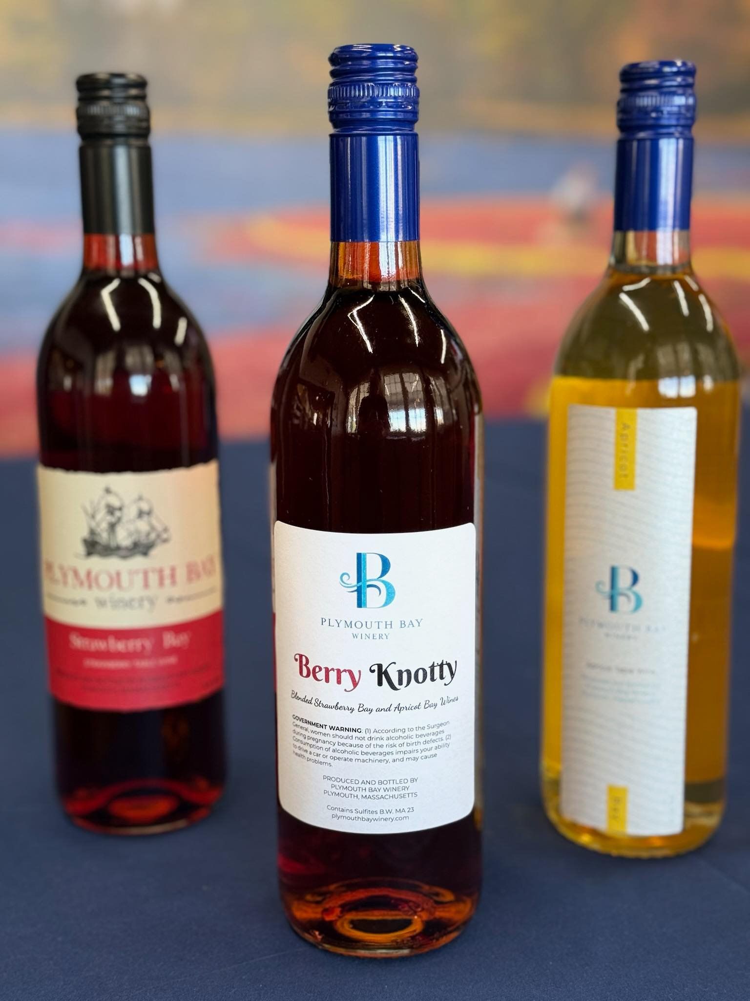 Three wine bottles with colorful labels on a table.