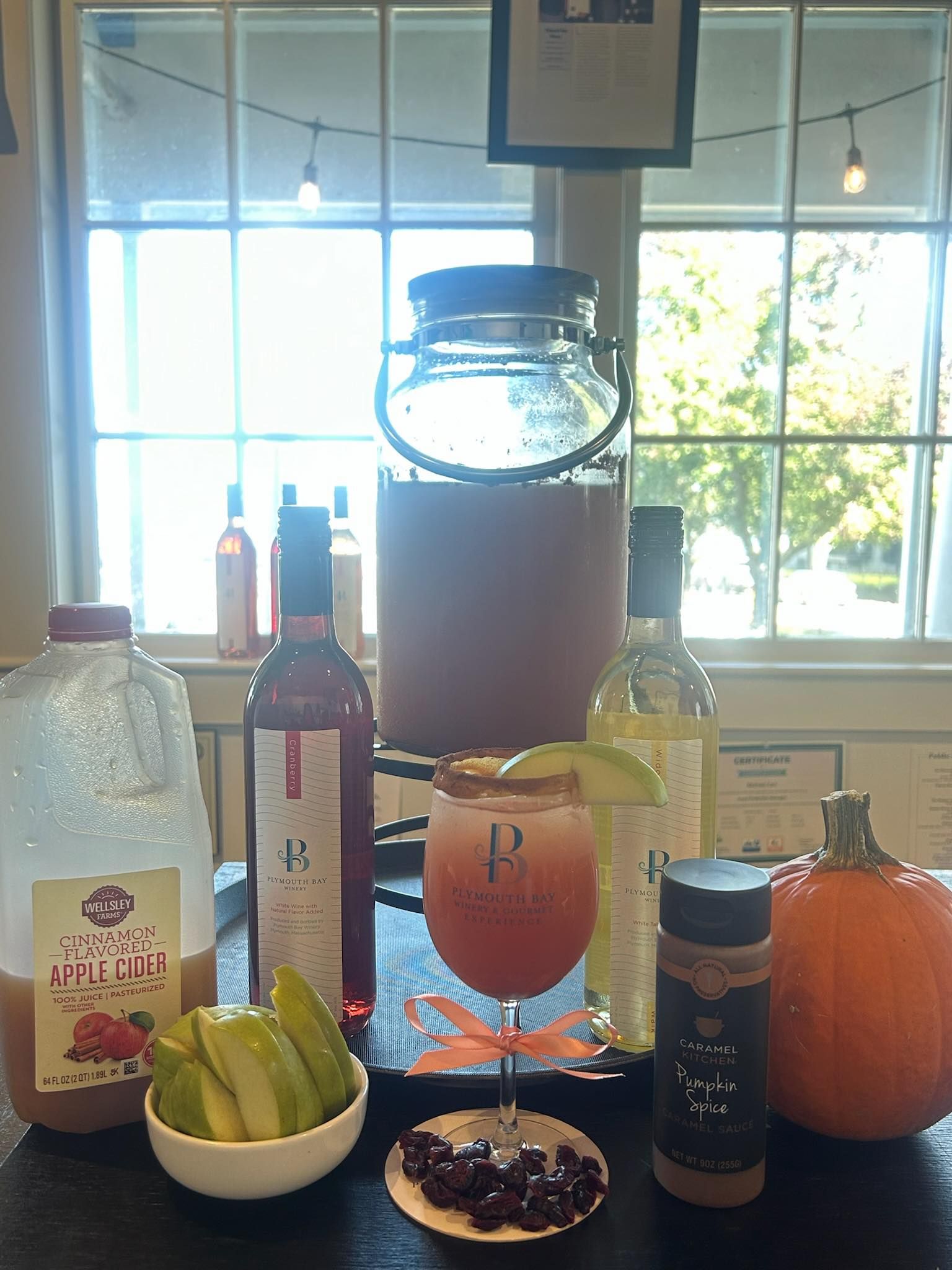 Autumn cocktail display: apple cider, wine bottles, pumpkin, glassware, and cinnamon.