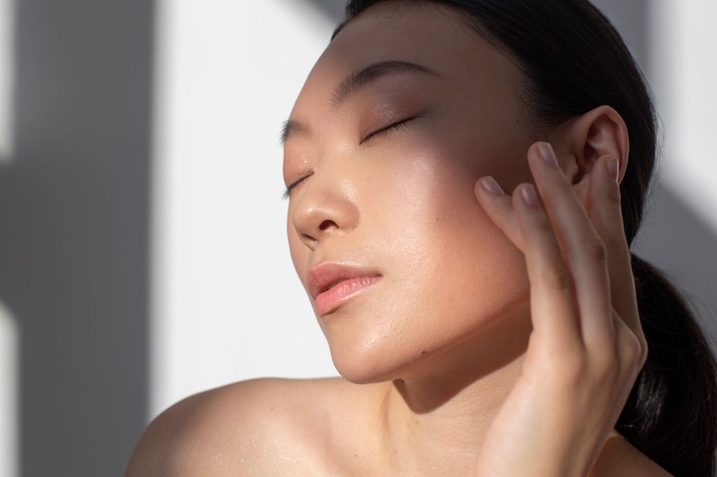 A woman is smiling and touching her face with her hands.