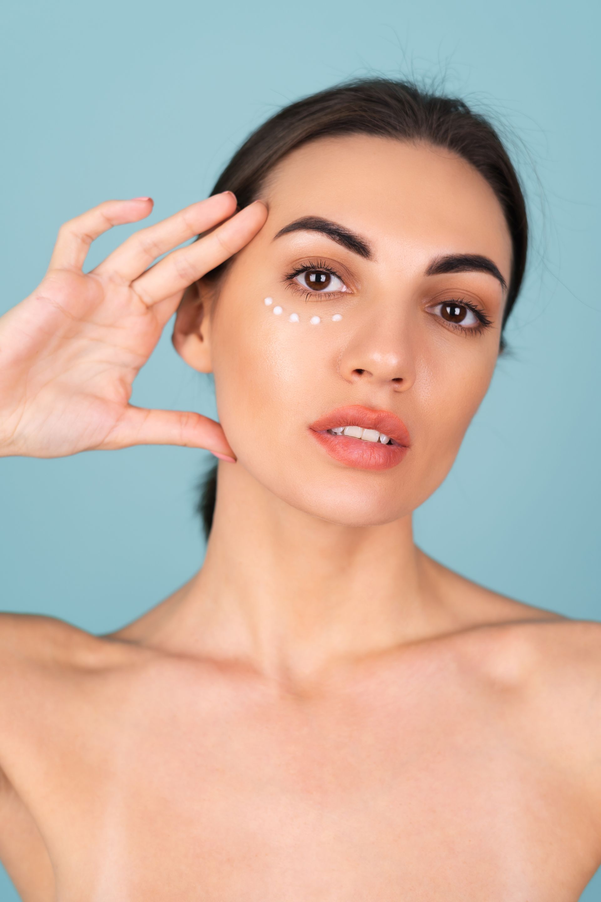 A woman is applying eye cream to her face.