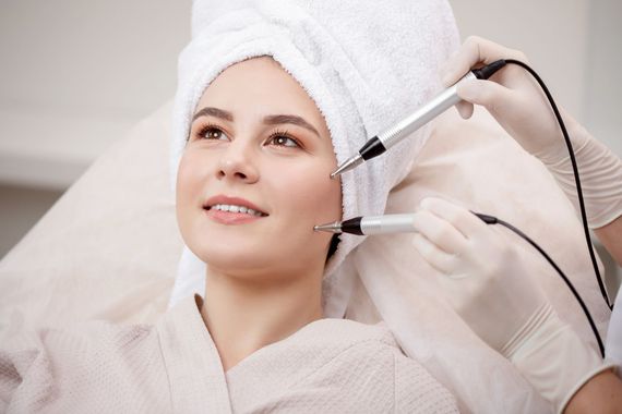 A woman with a towel wrapped around her head is getting a facial treatment.