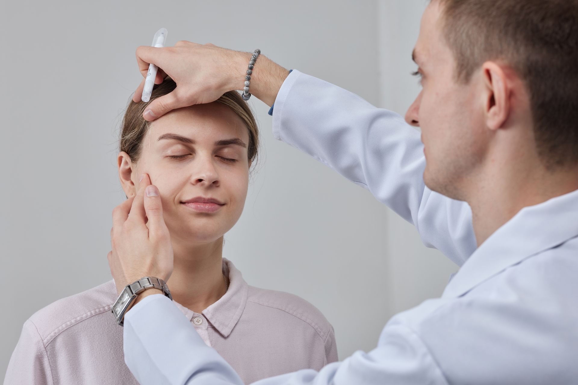 A doctor is examining a patient 's face with a pen.