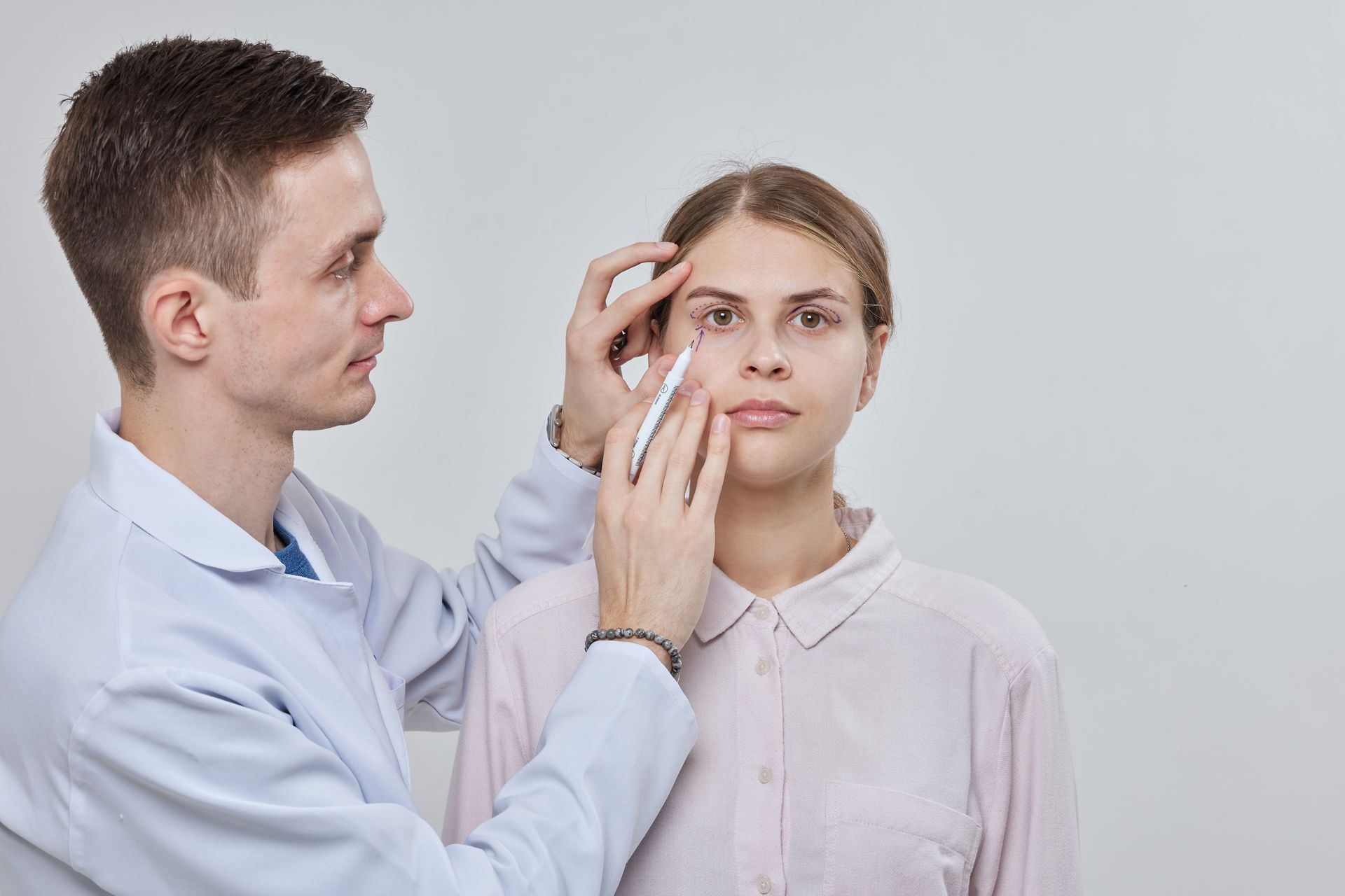 A man is examining a woman 's eye with a syringe.