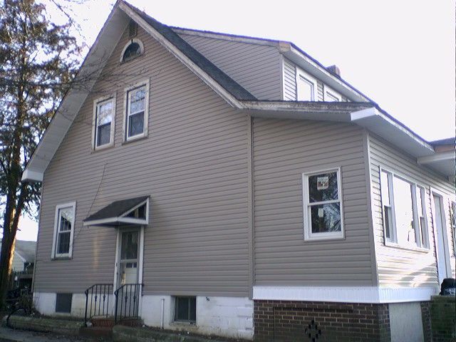 Two-story house with beige siding, white trim, and a brick foundation.