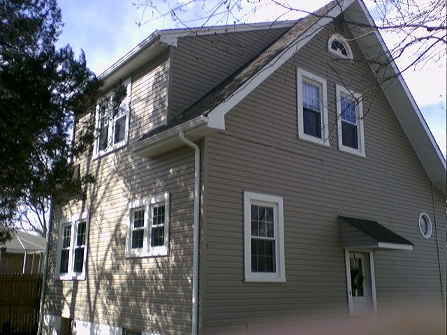 Tan house with white trim, multiple windows, and a small door awning.