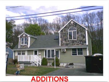 Green house with stone facade, additions text below, trees in background, blue sky.