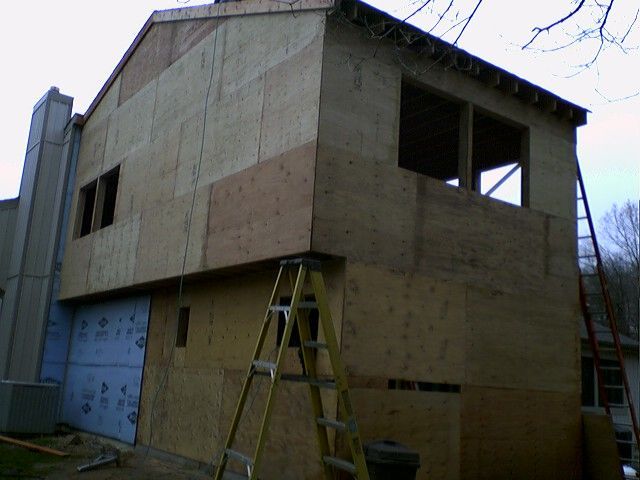 Construction site: Two-story building with exposed plywood, ladders, and unfinished window frames.