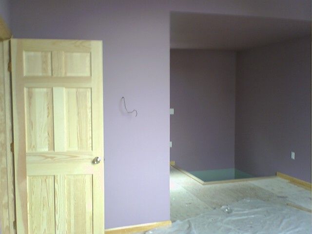 Interior with lavender walls, wooden door, and a recessed area.