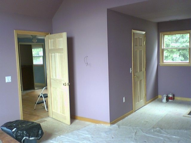 Room with light wood doors and trim, purple walls, and a window.