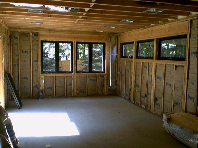 Interior of a room under construction with windows and insulation in the walls.