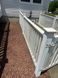 White railing leads to basement stairs with gravel path.