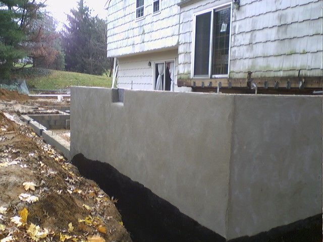 Concrete foundation wall under construction, next to a house.