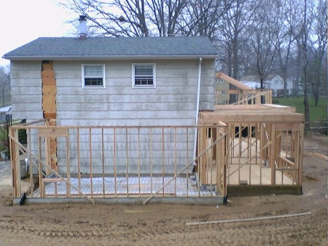 Framing of a deck being constructed next to a light-colored house.