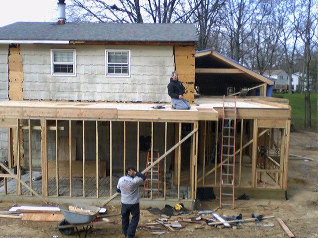 Construction of a house extension; workers on the framework. Daytime, outdoors.