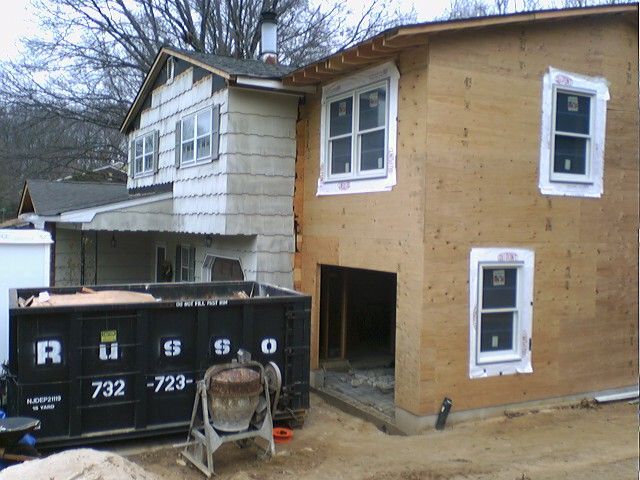 House under construction with a new addition; dumpster and cement mixer in the foreground.