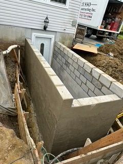 Basement entryway under construction. Concrete walls with block, dirt, and truck.