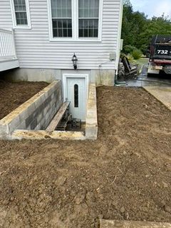 Exterior view of a house with a cellar door. The door is accessible via a recessed concrete entrance.