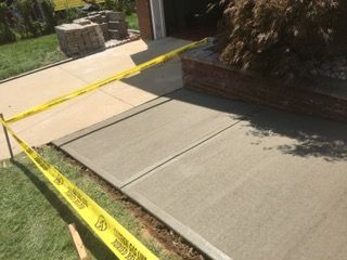 Freshly poured concrete sidewalk with yellow caution tape.