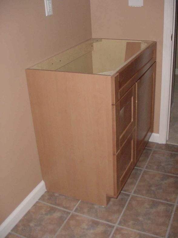 Brown cabinet installed in a corner on a tiled floor, with beige walls.