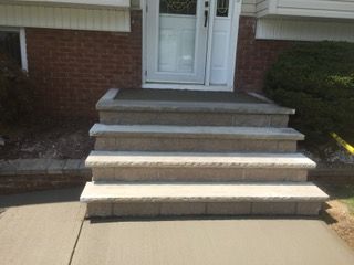 Stone steps leading up to a white door on a brick house.